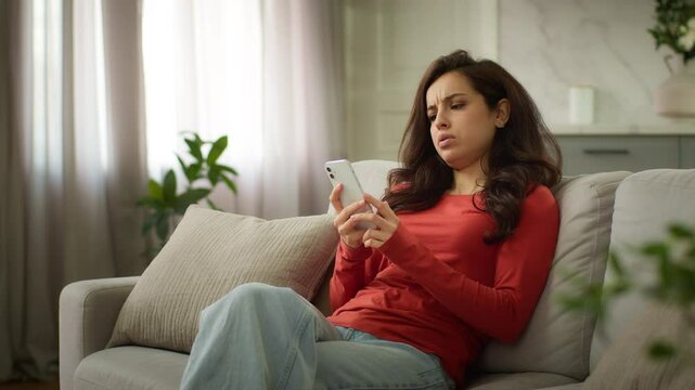 Stressed unhappy angry Caucasian female woman girl businesswoman customer at home couch shocked user using mobile phone confused cellphone device problem bad connection online error spam loss stress