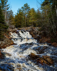 A cascading waterfall in the wilderness on a sunny blue sky day.