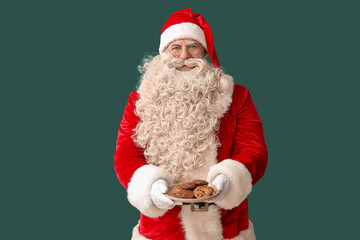 Santa Claus with plate of tasty cookies on green background