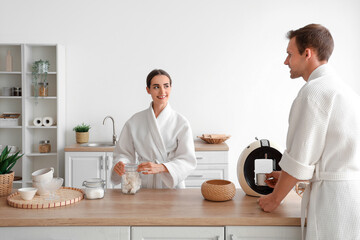 Young couple with marshmallows making coffee after shower in kitchen