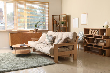 Interior of stylish living room with beige couch, wooden commode and shelf units