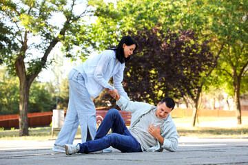 Young woman with her husband having heart attack on street