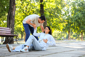 Young man and his wife having heart attack in park