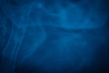 A close-up of soft, swirling blue smoke patterns creating an ethereal and dreamy abstract effect against a dark background