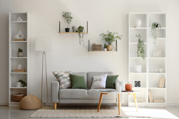 Cozy sofa, coffee table, shelving units and floor lamp in interior of living room