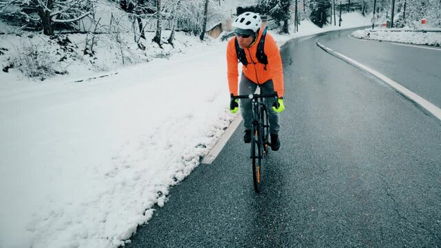 A man rides up a mountain road in winter as snow falls, French Alps close to Grenoble