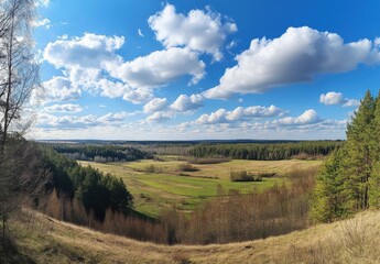 Obraz premium Panoramic View of Lush Green Landscape with Rolling Fields and Majestic Clouds under Bright Blue Sky in Serenity of Nature