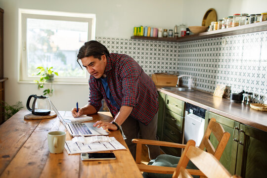 Man managing finances and working from home in kitchen