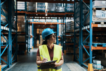Female warehouse worker inspecting inventory with clipboard