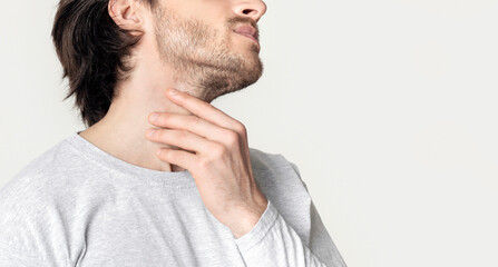 Obraz premium Man with throat sore is holding aching spot, cropped, panorama