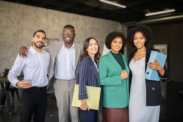 A group of diverse professionals gathers in a contemporary office, sharing ideas and documents. Their teamwork symbolizes cooperation and success in their careers.