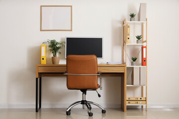 Interior of light office with workplace, shelf unit and blank frame