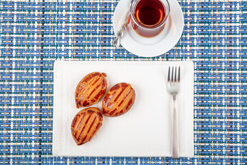 Traditional Turkish Dessert with Tea: Sekerpare. Sekerpare is served with tea on a white plate.