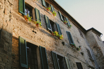 Stone building with shutters and flower pots.
