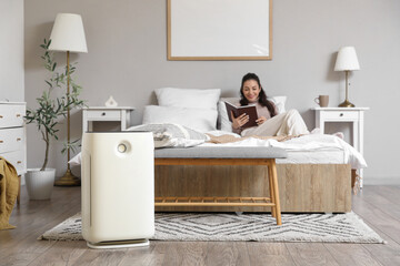 Air purifier against woman reading book in bedroom