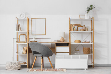 Interior of light office with workplace, shelf units and electric convector heater