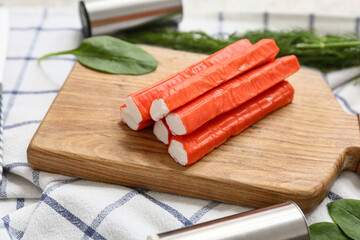 Wooden board with tasty crab sticks and spinach leaves on napkin, closeup © Pixel-Shot