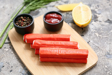 Wooden board with tasty crab sticks and different spices on grey background © Pixel-Shot