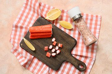 Wooden board with tasty crab sticks and cut lemon on beige background © Pixel-Shot