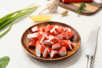 Wooden plate with cut tasty crab sticks and green onion on white background, closeup © Pixel-Shot