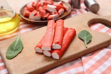 Wooden board and plate with tasty crab sticks on beige background © Pixel-Shot