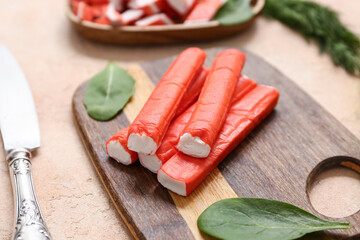 Wooden board with tasty crab sticks and spinach leaves on beige background © Pixel-Shot