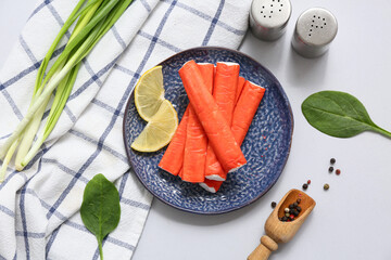 Plate with tasty crab sticks, slices of lemon and green onion on grey background © Pixel-Shot