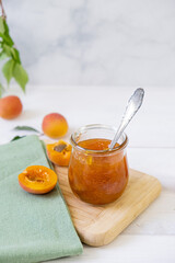 Homemade apricot jam in glass jar on kitchen white background. Summer harvest and canned food. 