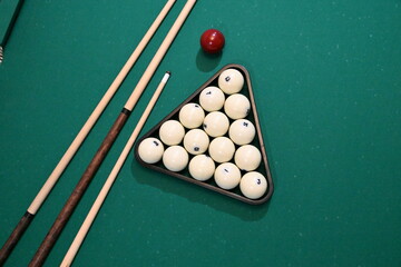 Balls collected in triangles and cues on a green background of a billiard table