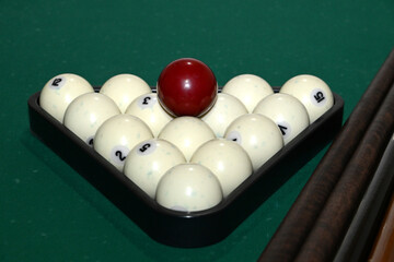 Balls collected in triangles and cues on a green background of a billiard table