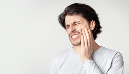 Young man suffering from terrible strong teeth pain