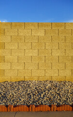 Obraz premium Block fence segment with a gravel xeriscaped ground at its base and clear blue morning blue sky above, copy space
