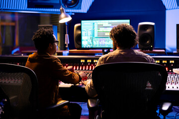 Team of artist and technician working on track recording in control room, mixing and processing...