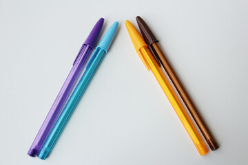 Colorful ballpoint pens arranged in triangular shape on white background. Cool and warm colors. Creative stationery, office supplies, creativity art lesson, back to school concept.	
