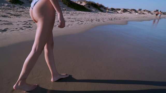 Piernas de chica joven paseando por la orilla del mar en la playa un d&iacute;a sensacional de vacaciones en verano.