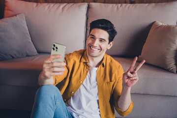 Young man enjoying a relaxing day at home taking a selfie on the couch in casual style