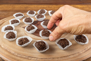 Male hand picking up a Brazilian chocolate truffle over wooden plates_9.