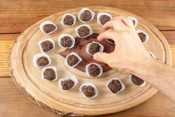 Male hand picking up a Brazilian chocolate truffle over wooden plates_10.