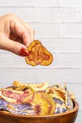 Woman picking up a colorful peruvian potato chip from wooden bowl