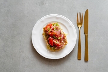 Belgian potato waffles served with ham, tomatoes and herbs with cutlery on a concrete background. Healthy breakfast, savory waffles