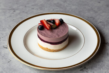 Blueberry cheesecake with fresh berries on a white plate, vertical