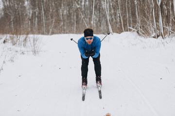Cross-country skier training on a snowy forest trail in winter