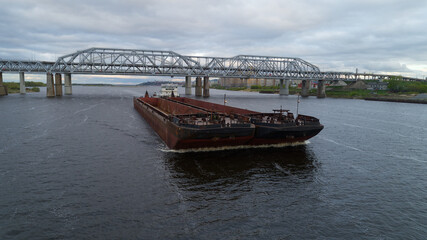 Large ship is crossing a bridge over a river