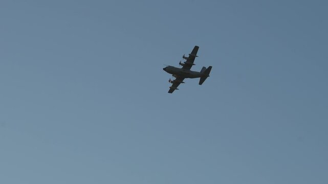 Marina di Pisa, Province of Pisa, Italy - November 4, 2024: A cargo plane flies over the sea in the rays of the evening sun. Military aircraft C-130 Super Hercule