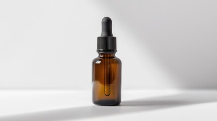 Naklejka premium Amber glass dropper bottle with black lid on a minimalist white surface, ideal for essential oils or skincare products.