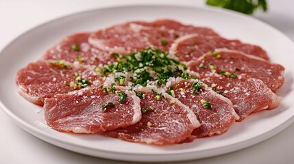 Fototapeta premium Veal carpaccio thinly sliced and arranged on a white plate with herbs and seasoning for an elegant culinary presentation