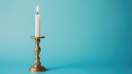 Elegant vintage gilded candlestick with lit candle against a serene blue background creating a classic ambiance for decor and photography purposes