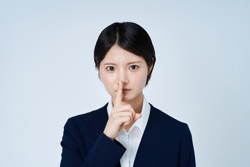 口に手を当てるスーツ姿の若い女性