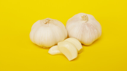 a bunch of garlic with husk on a yellow background.