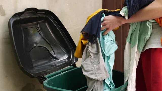 A young man throws away old clothes. Overflowing closet problem result in textile waste